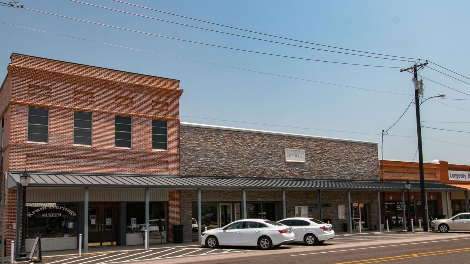Brick storefronts and a city hall building, illustrating downtown Krum, TX